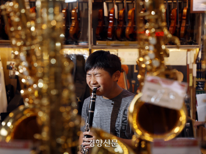 엄마와 낙원상가를 찾은 김민구군이 이날 구입한 클라리넷을 처음으로 불어보고 있다. 30년 전 ‘엄마의 엄마’는 이곳에서 딸에게 피아노를 사주었다. 악기와 음악인의 ‘성지’로 불리는 낙원상가는 올해 완공 50년이 됐다. /강윤중 기자