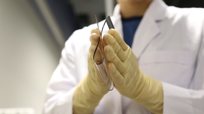 코오롱인더스트리 연구원이 세계 최초로 개발한 투명PI필름인 CPIⓡ필름을 접어보이고 있다. 코오롱인더스트리 제공