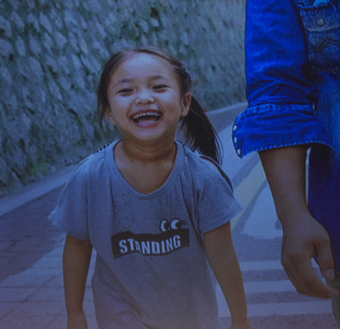 2017년 11월 카렌족 난민 토크 콘서트 공연 당시 무대 뒤편 스크린에 한국 재정착 카렌 난민 가족 아이 보라의 웃는 모습이 보인다. 유엔난민기구 제공