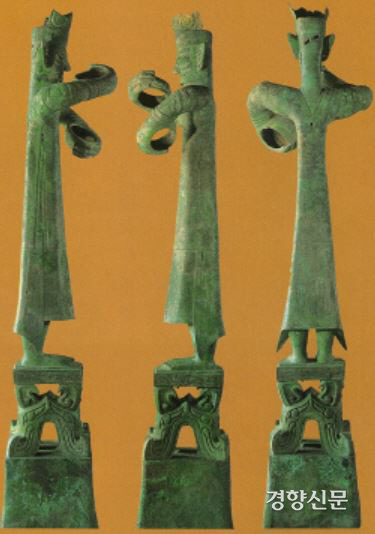 청동으로 만든 서있는 사람상. 전신을 다 갖춘 인물상이다. 옷자락에 4마리 용이 새겨져있다. 용은 후대에 황제나 임금을 상징하는 신령한 동물이다. 또 무언가를 쥐고 있는 모습이다.