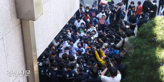 27일 광주지법에 도착한 전두환 전 대통령이 법정 건물로 들어간 뒤 소복을 입은 5월 어머니회 회원들이 사죄를 촉구하고 있다.