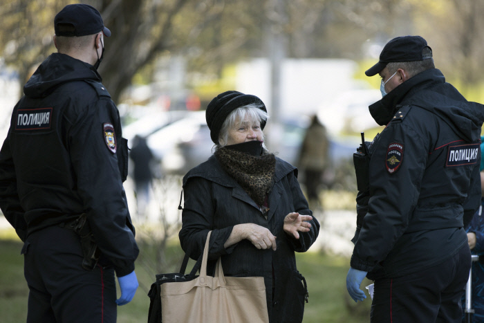 28일(현지시간) 러시아 모스크바에서 마스크를 쓴 경찰이 지나가던 여성의 통행허가를 검사하고 있다. 코로나19 봉쇄조치로 모든 시민들은 외출을 하려면 당국의 사전 허가를 받아야 한다.  모스크바 | AP연합뉴스