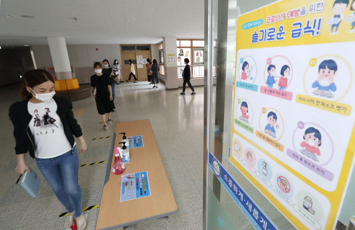 등교수업을 하루 앞둔 26일 경기 수원시 천일초등학교 1학년 교실에서 교사들이 입학 후 처음 등교하는 아이들의 준비물을 챙기고 있다(위 사진). 세종시 소담중학교에서도 교사들이 학생들의 이동 예상 동선을 따라가며 보완점을 점검하고 있다.  이준헌 기자·연합뉴스