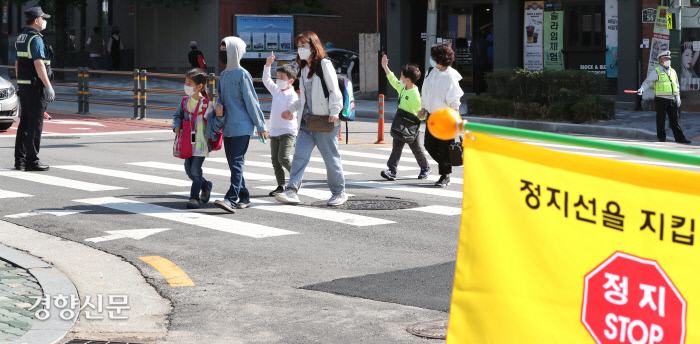 민식이법 시행 이후 초등학교 1~2학년이 27일 처음으로 등교했다. 서울 성북구 정덕초등학교 앞 횡단보도에서 경찰과 교통안전 자원봉사자들이 학생들과 학부모들의 안전한 등교를 돕고 있다. 권호욱 선임기자