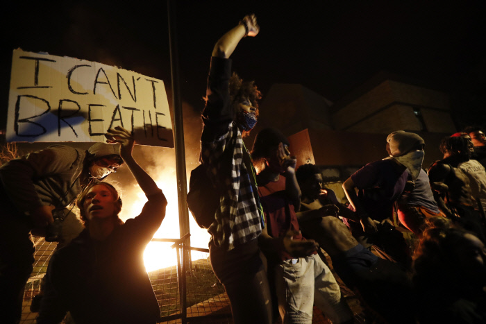 28일(현지시간) 밤 미국 미네소타주 미니애폴리스의 경찰서 주변 불타는 건물 옆에서 시위대들이 구호를 외치고 있다.  미니애폴리스｜AP연합뉴스