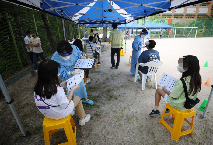 20일 오후 서울 성동구 옥수초등학교 운동장에 설치된 선별진료소에서 이 학교 6학년 학생, 교직원들이 코로나19 검사를 받기 위해 대기하고 있다. 연합뉴스.