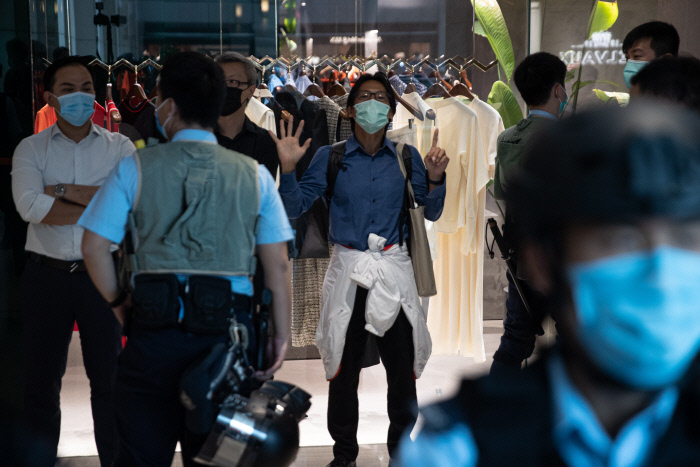 한 쪽에선 축배, 한 쪽에선 게릴라 시위…전운 감도는 홍콩 중국 전국인민대표대회 상무위원회가 홍콩 국가보안법안을 통과시킨 30일 홍콩의 친중국 시위대가 길거리에서 샴페인을 부어 마시며 입법을 환영하고 있다(왼쪽 사진). 반면 게릴라 시위 장소가 된 홍콩의 한 쇼핑몰에서는 경찰의 삼엄한 감시 아래 한 시민이 보안법 반대 구호를 외치고 있다.  홍콩 | 로이터·EPA연합뉴스