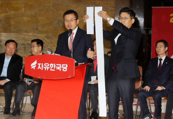 ‘투표용지 길이 비교’ - 23일 국회 로텐더홀에서 열린 자유한국당 최고위원회의에서 황교안 대표가 연동형 비례제를 비판하는 동안 성동규 여의도 연구원장이 길어진 가상의 투표용지를 보여주고 있다. 2019.12.23 연합뉴스