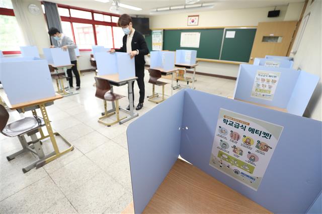 학교급식 에티켓 지키기 - 신종 코로나바이러스 감염증(코로나19) 확산으로 연기됐던 고3 학생들의 등교 개학을 하루 앞둔 19일 오전 대구 수성구 정화여자고등학교 3학년 교실에서 교사들이 코로나19 예방을 위해 책상 위에 설치된 가림막을 점검하고 있다. 학교 조리실에서 급식을 준비해 교실에서 배식과 식사를 하는 학생들을 위해 가림막 안쪽에는 학교급식 에티켓 안내문이 붙어 있다. 2020.5.19/뉴스1