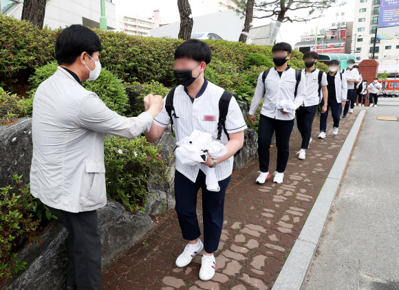 고등학교 3학년 등교가 시작된 20일 오전 경기도 수원시 팔달구 수원고등학교에서 학생들이 등교하며 교사와 주먹인사를 하고 있다. 연합뉴스.