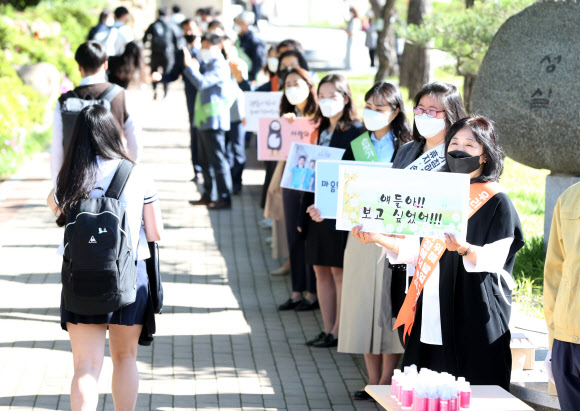 20일 오전 경북 포항 영일고에서 신종 코로나바이러스 감염증(코로나19)으로 집에서 수업을 받던 고교 3학년 학생들이 처음으로 등교하자 교사들이 “얘들아 보고 싶었어”라고 쓴 손팻말을 들고 환영하고 있다. 연합뉴스.