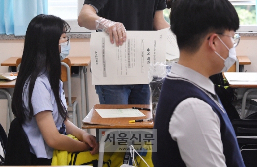 개학 다음날 수능 모의평가 치른 고3 - 5월 전국연합학력평가가 21일 시행된 가운데 수원시 조원고등학교 3학년 교실에서 비닐장갑을 낀 담임 교사가 마스크를 쓴 학생들에게 1교시 국어영역 시험지를 나눠주고 있다. 코로나19 확산으로 이번 시험은 사실상 올해 처음 치러진 수능 모의평가였다.오장환 기자 5zzang@seoul.co.kr