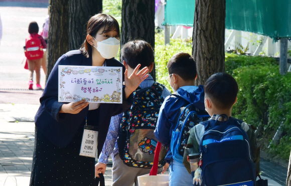 고등학교 2학년과 중학교 3학년, 초등학교 1∼2학년, 유치원생들이 등교 수업을 시작한 27일 오전 서울 송파구 세륜초등학교에서 학생들이 환영하는 손팻말을 든 선생님과 인사하며 교실로 향하고 있다.2020.5.27. 이종원 선임기자 jongwon@seoul.co.kr