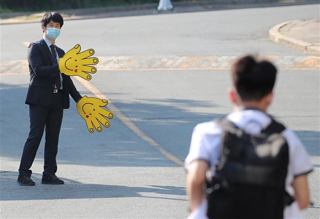 등교 인사하는 대구 - 2차 등교 개학 이틀째인 28일 대구의 한 중·고등학교 정문에서 마스크를 쓴 등교지도 교사가 손 모양의 큰 장갑을 끼고 학생들과 인사를 나누고 있다.대구 뉴스1