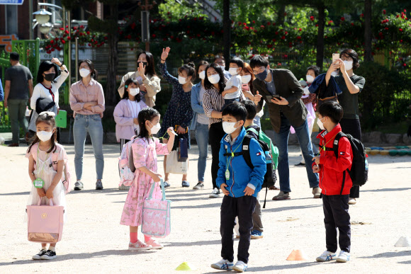 “교실서 마스크 벗지 마” “수업 잘 받고 올게요” - 2차 등교수업이 시작된 27일 서울 종로구 청운초등학교에서 마스크를 낀 1·2학년 학생들이 엄마, 아빠와 작별 인사를 하고 있다. 연합뉴스