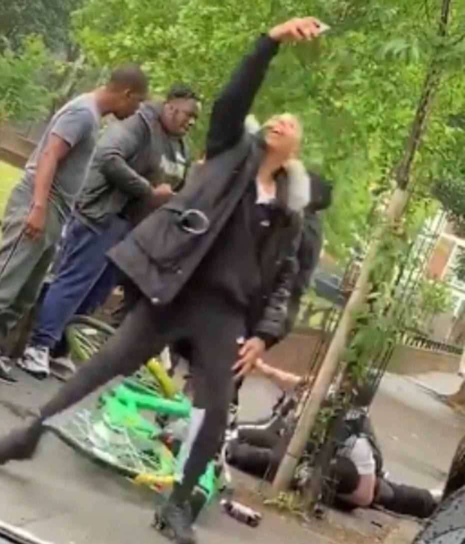 백인 경찰이 폭행 당하는 모습을 보고 기념사진을 찍고 있는 흑인 행인