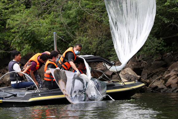 대북전단 풍선 수거하는 경찰 - 지난 22일 밤 경기 파주에서 탈북단체가 보낸 대북전단 살포용 풍선이 23일 홍천군 서면 마곡리 인근 야산에 떨어져 경찰이 수거하고 있다. 발견된 대북전단 살포용 풍선은 2∼3m 크기로, 김정은 북한 국무위원장 일가의 사진이 부착돼 있다. 2020.6.23 연합뉴스
