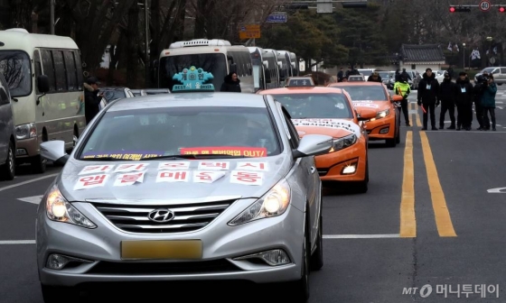 지난해 12월 카풀 도입 반대 문구를 택시에 부착한 채 대통령과의 면담을 요구한 뒤 떠나고 있다. / 사진=홍봉진 기자 honggga@