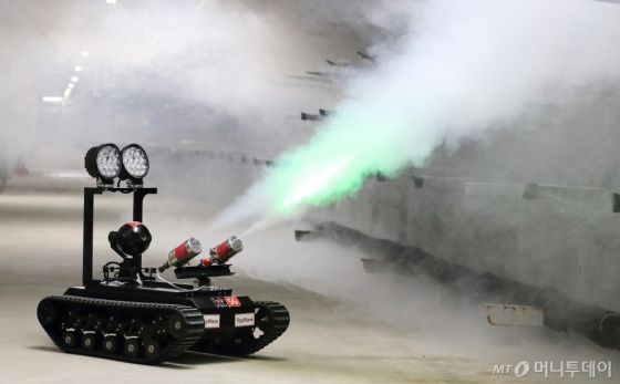 통신구에 설치된 지상형 5G 로봇이 비정상적으로 온도가 상승한 지점으로 출동해 로봇에 탑재한 에어로졸 소화기로 소화분말을 분사하고 있다./사진제공=KT