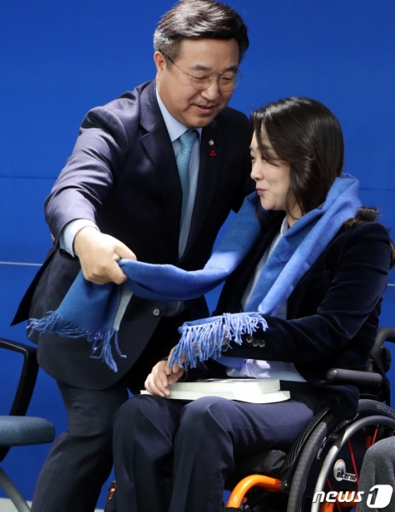 (서울=뉴스1) 이종덕 기자 = 윤호중 더불어민주당 사무총장이 26일 서울 여의도 더불어민주당 중앙당사에서 21대 총선 민주당 인재영입 1호인 최혜영 교수에게 파란색 목도리를 전달하고 있다. 민주당 인재영입 1호는 발레리나 출신 척수장애인 최혜영 교수다. 2019.12.26./뉴스1