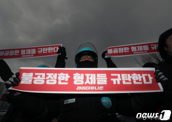 (서울=뉴스1) 구윤성 기자 = 배달원들의 권익보호 단체인 라이더유니온 회원들이 17일 오후 서울 송파구 우아한형제들 본사 앞에서 열린 배달료 삭감 반대 집회에서 '배달의민족' 운영사인 우아한형제들을 규탄하는 피켓을 들고 있다.  라이더유니온은 우아한형제들이 배달료 체계와 근로조건 등에 대해 상반된 주장을 한다며 안전운행이 가능한 수준의 배달료 인상과 지역 차별 개선, 배차 애플리케이션 운영 방식 개선, 일부 배민 커넥터의 불법 행위 단속 강화 등을 요구했다. 2020.2.17/뉴스1