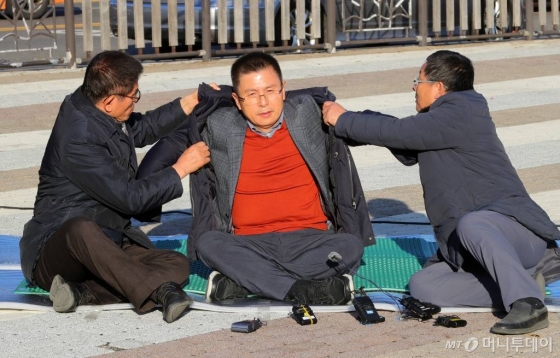 황교안 미래통합당 대표가 지난해 12월 20일 오후 청와대 분수대에서 총체적 국정실패 규탄을 위한 단식 투쟁에 들어간 뒤 김문수(왼쪽) 전 경기지사, 차명진 전 의원의 도움을 받아 점퍼를 입고 있다. /사진제공=뉴시스