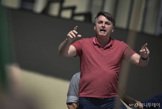 [브라질리아=AP/뉴시스]자이르 보우소나루 브라질 대통령이 지난 19일 브라질리아에서 신종 코로나바이러스 감염증(코로나19) 확산을 막기 위한 사회적 거리두기 등 규제 해제를 요구하는 시위에 참가해 연설하고 있다. 보우소나루는 이날 가끔 기침을 하는 모습을 보이면서도 마스크를 착용하지 않았다. 그는 20일에는 규제 조치들이 이번주 내로 끝나기를 희망한다고말했다. 2020.4.21