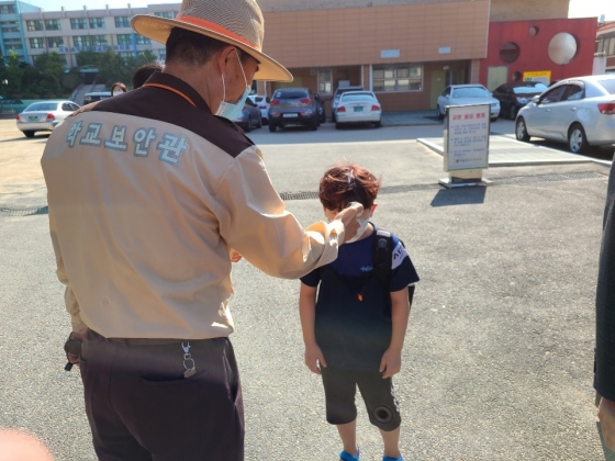 27일 서울 구로구 소재의 한 초등학교 앞에서 학교 관계자가 아이의 체온을 확인하고 있다. /사진=정한결.