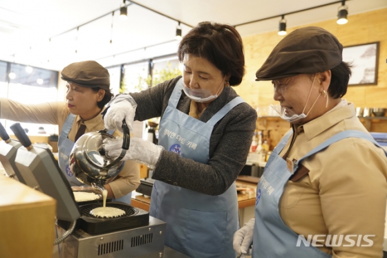 [서울=뉴시스김정숙 여사가 16일 오후 강원 동해시 동해시니어클럽 ‘행복한 디저트카페’를 방문해 바리스타 어르신들로부터 와플기계 사용법을 배운 후 와플을 굽고 있다.(사진=청와대 제공) 2019.12.16.   photo@newsis.com