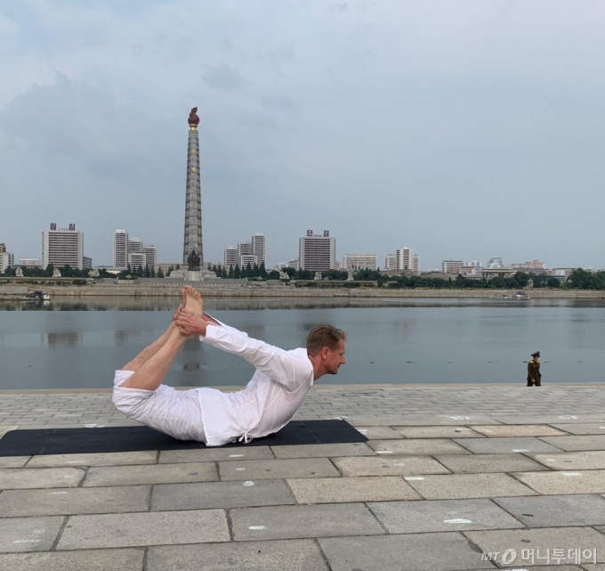 대동강변 주체탑을 배경으로 요가 중인 요아힘 버그스트롬 주북한 스웨덴 대사. 오른쪽에는 마스크를 쓴 북한 군인이 보인다./사진=로이터 선임특파원 Josh Smith 트위터