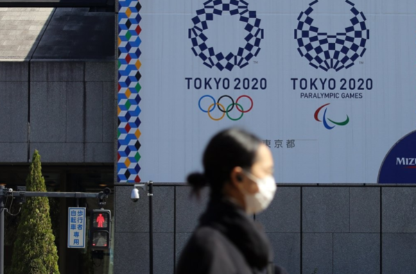 마스크를 쓴 여성이 도쿄 올림픽·패럴림픽 홍보물이 설치된 일본 도쿄도(東京都) 지요다(千代田)구의 거리를 지나가고 있다. /연합뉴스