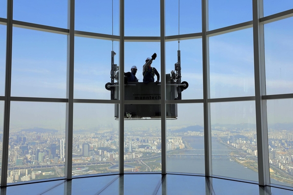 청소업체 직원들이 서울 잠실 롯데월드타워 외벽 유리창을 청소하고 있다. /롯데물산 제공