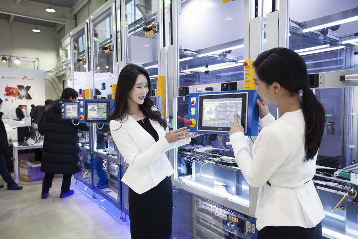 SKT모델들이 5G 스마트 유연생산 설비를 통해 소형IoT 기기가 만들어지는 과정을 지켜보고 있다.