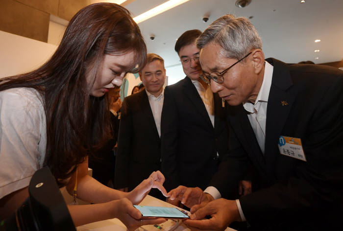 윤종규 KB금융지주 회장과 손병두 금융위원회 부위원장, 하현회 LG유플러스 부회장(오른쪽부터)이 28일 서울 중구 반얀트리 클럽앤 스파 서울에서 열린 리브모바일(LIIV M)론칭행사에서 대화형 금융플랫폼 리브 똑똑 체험을 하고 있다.