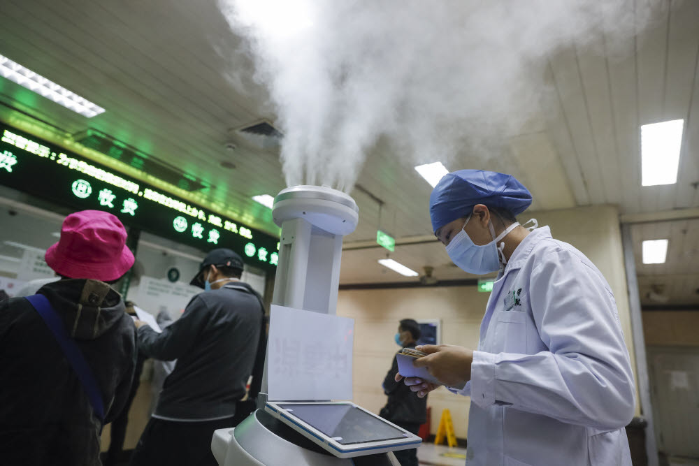 WUHAN, March 19, 2020 (Xinhua) -- A medical worker uses a tablet computer to control a disinfecting robot at Renmin Hospital of Wuhan University in Wuhan, central Chinaapos;s Hubei Province, March 16, 2020. TO GO WITH XINHUA HEADLINES OF MARCH 19, 2020. (Xinhua/Shen Bohan)