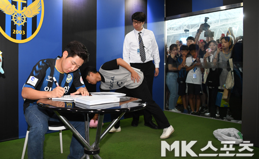 사인회에 들어가지 못한 팬들이 대형 창문을 통해 이강인의 모습을 바라보고 있다.