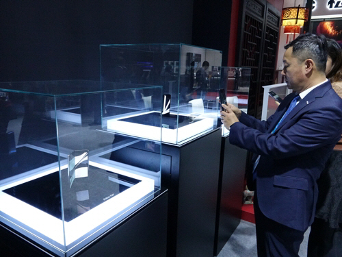 5일 중국 상하이에서 진행 중인 제2회 중국국제수입박람회의 삼성 전시장에서 관람객들이 유리 상자 속에 놓인 갤럭시폴드를 살펴보고 있다. [사진 출처 = 연합뉴스]