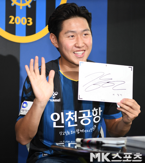 사인회에서 사인지를 들고 미소를 짓고 있다.