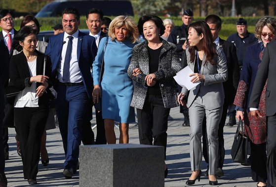 김정숙 여사와 에마뉘엘 마크롱 대통령의 부인 브리지트 마크롱 여사가 15일 프랑스 파리 루브르박물관으로 향하고 있다. 이 날 김정숙 여사가 마크롱 여사와의 만남에서 입은 자켓은 프랑스를 대표하는 브랜드 샤넬이 한국에서 개최했던 2015/16 크루즈 컬렉션 무대에 소개되었던 작품이다. 샤넬을 대표하는 트위드 자켓은 검정색 배경에 '한국', '서울', '코코', '샤넬', '마드모아젤' 등의 한글을 흰 색으로 직조한 특별한 원단의 의상이다. 칼 라거펠트는 특히 ’한글이 세계에서 가장 아름다운 글자“라며 그 조형미를 극찬한 바 있다. [사진 뉴시스]