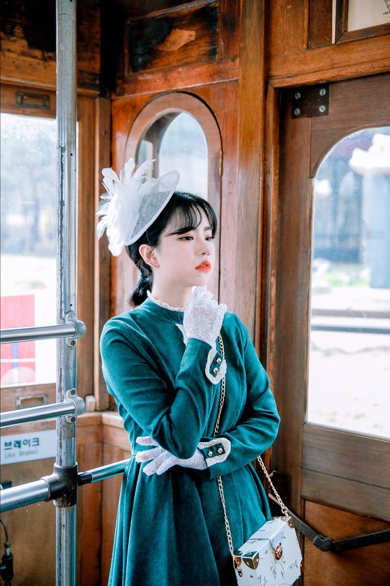 허리를 잘록하게 리본으로 묶은 원피스를 입고 망사 장식이 달린 모자를 쓴 모델. [사진 경성스타일]