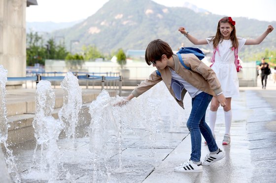 9일 오후 서울 종로구 광화문광장 분수대에서 외국인 어린이들이 물놀이를 즐기고 있다. [뉴시스]