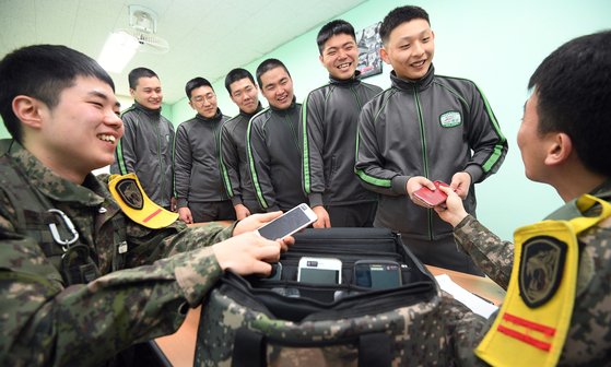 병(兵) 일과 후 휴대전화가 1일부터 전면 허용된다. 평일에는 오후 6시부터 10시까지, 휴일에는 오전 7시부터 10시까지 사용이 가능하다. 지난 1월 시범운영 부대인 경기도 가평군 육군 수도기계화보병사단 혜산진부대에서 오후 일과를 마친 병사들이 당직사관에게 휴대전화를 건네받고 있다. [뉴스1]