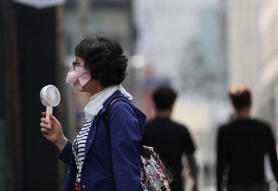 서울 한낮기온 27도의 초여름 날씨를 보인 15일 명동거리를 지나는 한 시민이 휴대용 선풍기로 더위를 식히고 있다. [연합뉴스]