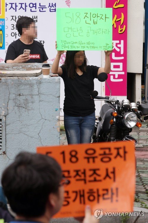 18일 오후 광주 동구 금남로에서 자유연대 등 일부 보수표방 단체가 5·18유공자와 관련한 의혹을 제기하는 집회를 열자 한 시민이 '5·18진압자 명단을 공개하라'는 손팻말을 들고 있다. [연합뉴스]