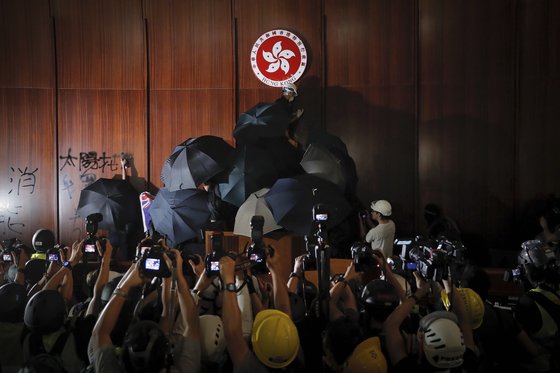 시위대가 의사당 벽 중앙에 걸린 홍콩특별행정구의 동그란 상징 그림 위에 검은 스프레이 칠을 하고 있다. [AP=연합뉴스]