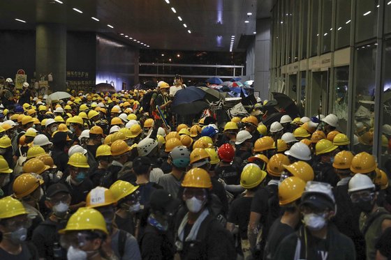 검은 옷을 입고 헬멧, 고글, 마스크로 얼굴을 가린 강경 시위대가 입법회 건물 입구에 모여있다. [EPA]