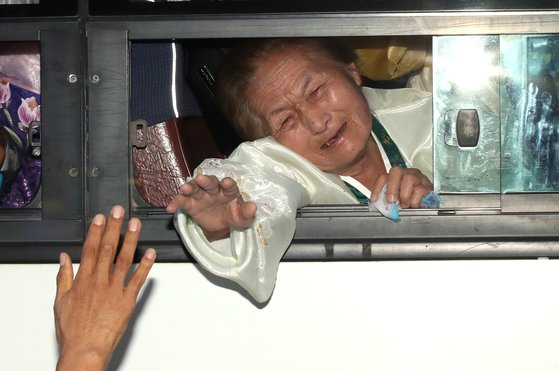 제21차 이산가족 상봉행사 2회차 마지막날인 26일 북한 금강산호텔에서 열린 작별상봉 및 공동중식을 마치고 버스에 오른 북측 가족들이 남측 가족들과 헤어지며 눈물을 흘리고 있다. [뉴스1]