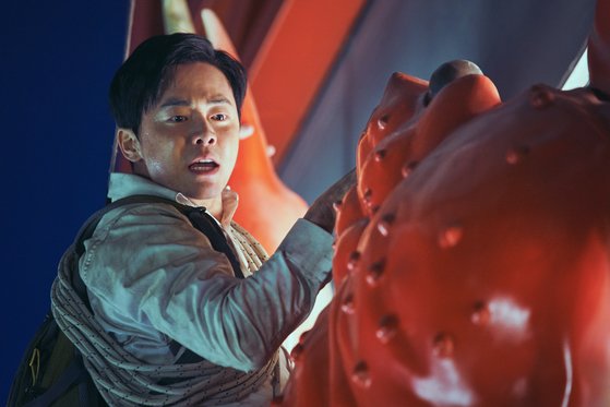 주인공 용남이 건물 외벽의 대게 모양 간판에 매달린 모습. 4DX 상영에선 스크린 속 이런 아찔한 동작에 맞춰 객석의 의자가 음직인다. 등받이에서 불어나온 바람이 목덜미를 스칠 땐 솜털까지 쭈뼛 솟는다.[사진 CJ엔터테인먼트]