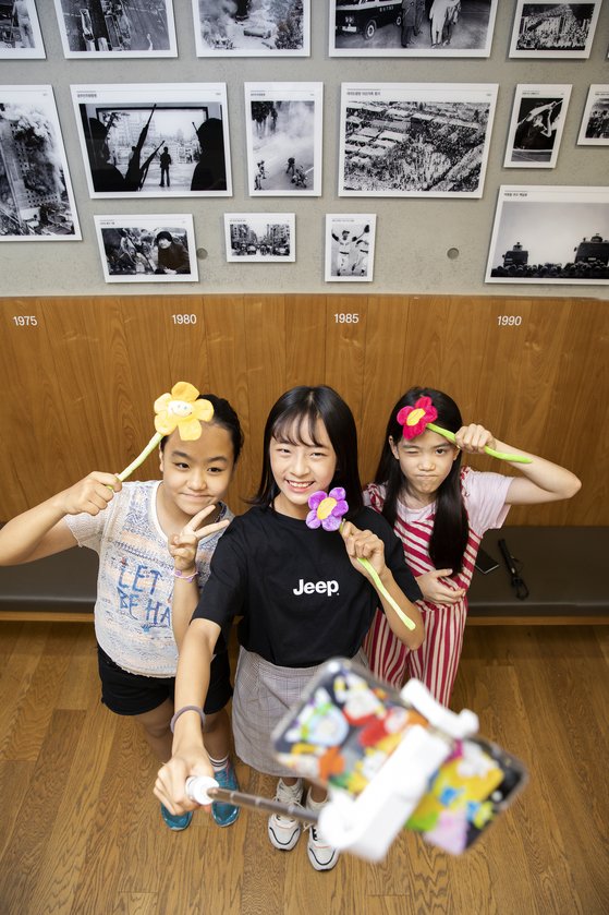 김은비 학생기자와 하람, 이수안 학생모델(왼쪽부터)이 하람이 준비한 유행 물건을 들어 보였다. 하람은 셀카봉을 길게 뽑아 손에 들고었다. 그는 소품을 이용한 셀카는 다양한 색감이 더해져 멋지다고 강조했다.