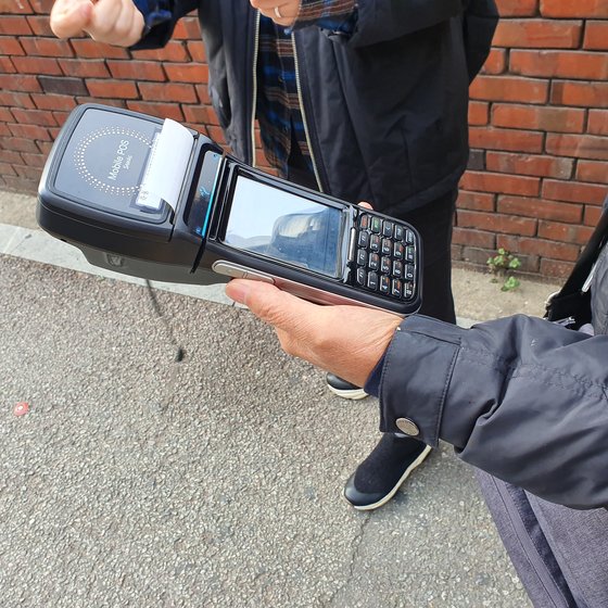 유씨가 늘 들고 다니는 기계. 현장에서 주민등록번호를 확인하고 과태료를 결제할 수 있다. 성동구보건소 건강생활팀 변우애 주무관은 "과태료를 빨리 납부하면 할인해주기도 하고, 고지서가 집에 오기를 꺼리는 경우도 있어 현장 납부를 하는 경우가 적지 않다"고 설명했다. 신혜연 기자.